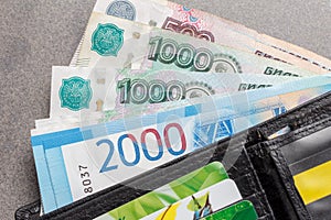 New Russian banknotes in denominations of 1000, 2000 and 5000 rubles and credit cards in a black leather purse close-up