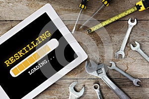Reskilling loading on digital computer tablet and tools supplies on wooden background