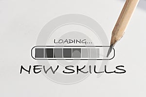 New skills loading written on white paper with processing symbol and pencil