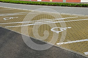 New sloping parking space with drawn lines and symbols for parking wheelchair users and people with disabilities. flowerbed with h
