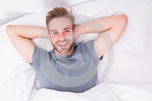 New smile, new day. Happy man awaken in bed. Handsome caucasian man with happy smile relaxing in the morning. Sparkling