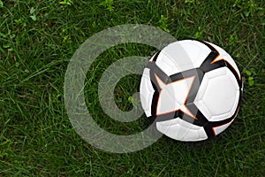 New soccer ball on fresh green grass outdoors, top view. Space for text