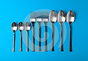 New spoons and forks on blue background