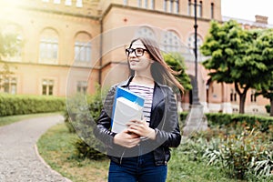 New study year begin. Female student holding notebooks outdoors and smiling on Uni background