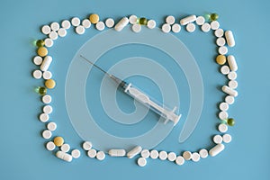 New syringe and pills and capsule on blue background, health and medical concept, drug overdose. Suringe and many tablets