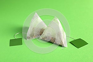 New tea bags with tabs on green background, closeup