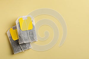 New tea bags with tabs on yellow background, flat lay. Space for text