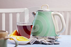 New teapot on table with cup of black tea and sliced lemon