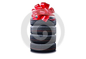 New tires pile as a gift  isolated on white. Tyres pile with a big red bow, as a present or bonus for buying a car