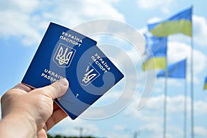 New ukrainian blue biometric passport with identification chip on against blue sky and waving flag background.