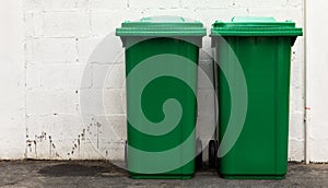 A new unbox green large bins ready to use on footpath and white concrete wall