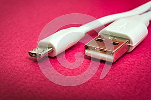 New USB charger cable on red surface closeup often used for charging smartphone or tablet