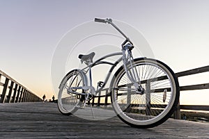 New vintage bike parked in the middle of the wooden boardwalk at sunset