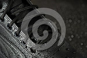 New waterproof leather winter boots with water drops on a black background close-up. Shoes concept.