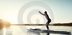 The new way to do yoga. an attractive young woman doing yoga on a paddle board on a lake outdoors.