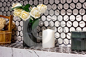 New white candles with the rose flowers bouquet in the vase on the shelf.