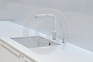 A new white kitchen sink made of artificial stone and a faucet. The concept of modern kitchen interior