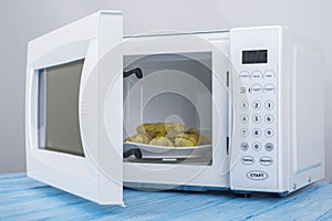 White microwave oven, on a blue wooden surface for heating food