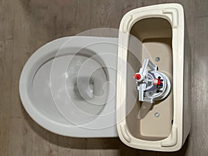 New white toilet tank with an open lid and flush system top view. Plastic toilet drain system