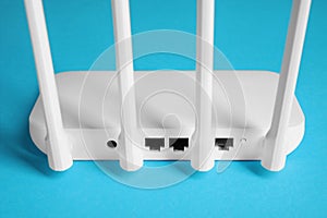 New white Wi-Fi router on blue background, back view