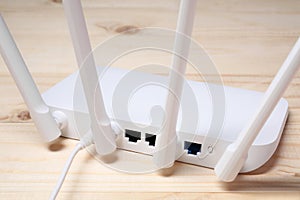 New white Wi-Fi router on wooden table, closeup