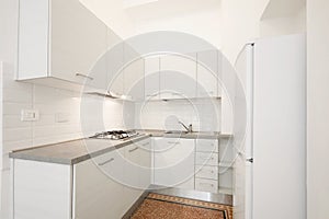 New, white wooden kitchen with gray stone top in renovated interior