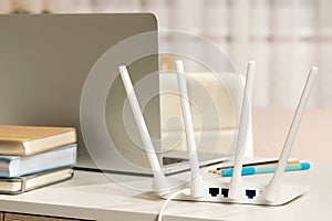 New Wi-Fi router near laptop on white table indoors