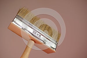 New wide paint brush on pink wall background