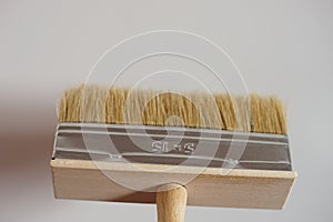 New wide paint brush on white wall background