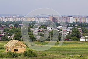 New wooden cottage of natural lumber materials under construction in quiet neighborhood on distant city buildings background. Pro