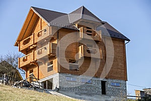 New wooden ecological traditional cottage house of natural lumber materials with shingle roof and stone basement under