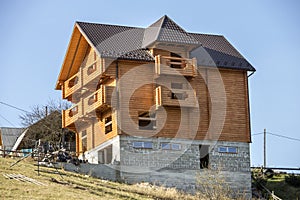 New wooden ecological traditional cottage house of natural lumber materials with shingle roof and stone basement under