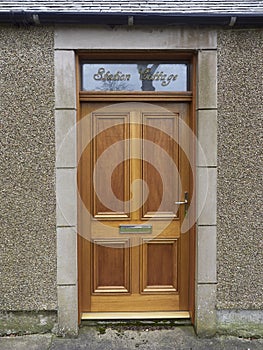 A new wooden Front Door with Brass Fittings set into an Old railway Cottage in the Village of Colliston.