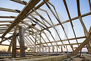 New wooden house under construction. Close-up of attic roof frame against clear sky from inside. Ecological dream home of natural