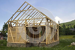 New wooden house under construction in quiet rural neighborhood. Timber frame of natural materials for walls and roof on stone fou