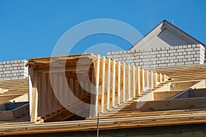 A new wooden roof structure lining a house in the city. Industrial roofing system with wooden beams, ceilings and tiles. Roofing