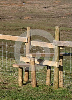 New wooden stile over wire fence in countryside