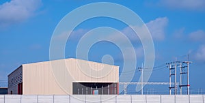 New workshop building with concrete fence wall and electric poles against blue sky background