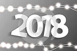 New Year 2018 concept with paper cuted white numbers on realistic Christmas lights decorations on grey background