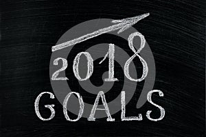 New Year 2018 goals with a rising arrow text chalk on a blackboard. Chalkboard written with text 2018 Goals. New year success in