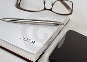 New Year 2018 office organizer calendar, smartphone, glasses and