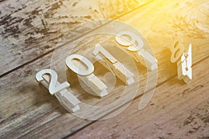 New year 2019 concept. Clothpin with number 2019 on wooden background with sun flare