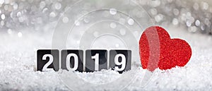 New year 2019 and a red heart on snow, abstract bokeh lights