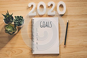 New year 2020 goals list. Office desk table with notebooks and pancil with pot plant