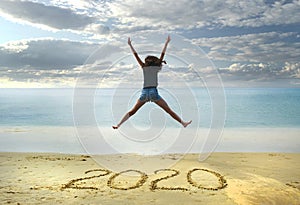 New Year 2020 on the sand,happy girl with hands up jumping on the beach