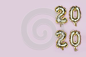New Year 2020. Vertical composition of number 2020 golden foil balloons on pastel pink background. Flat lay with copy