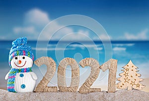 New Year 2021 on the beach. Snowman and Christmas tree in the sand