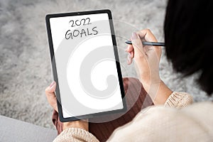 New year 2022 goals, plans concept with woman hand writing to lo list on tablet
