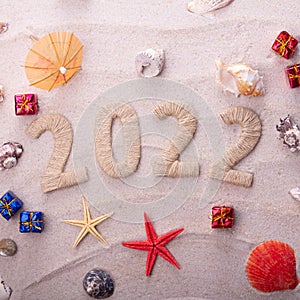 New year 2022 and sandy beach. Starfish and seashells with Christmas gifts