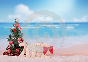 New Year 2022 sign with Christmas tree on beach background. Blank space for inscription